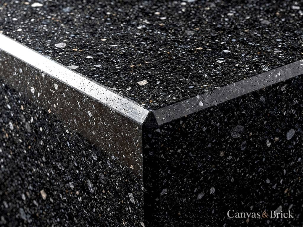Polished black granite countertop showing dense speckled mineral grain