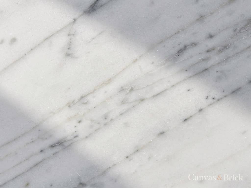 Honed white Italian marble with soft grey veining running across the slab