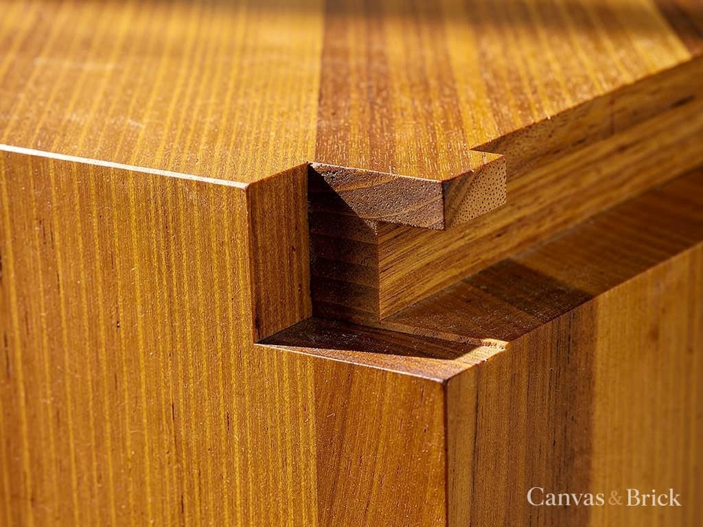 Solid seasoned teak showing straight grain and a mortise and tenon joint under an oil finish