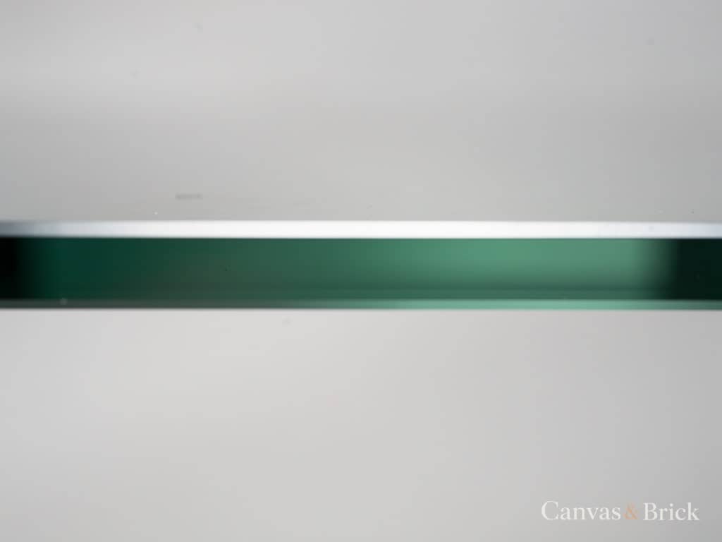 Polished edge of a clear toughened glass panel showing the green tint through its thickness